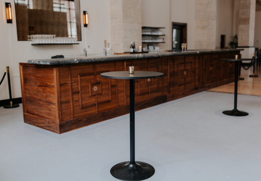 Long wooden bar prepared for cocktail service inside the grand hall at The Reserve wedding venue.