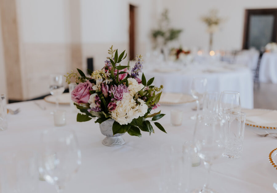 Soft pink and white floral centerpiece displayed on a wedding reception table setting.