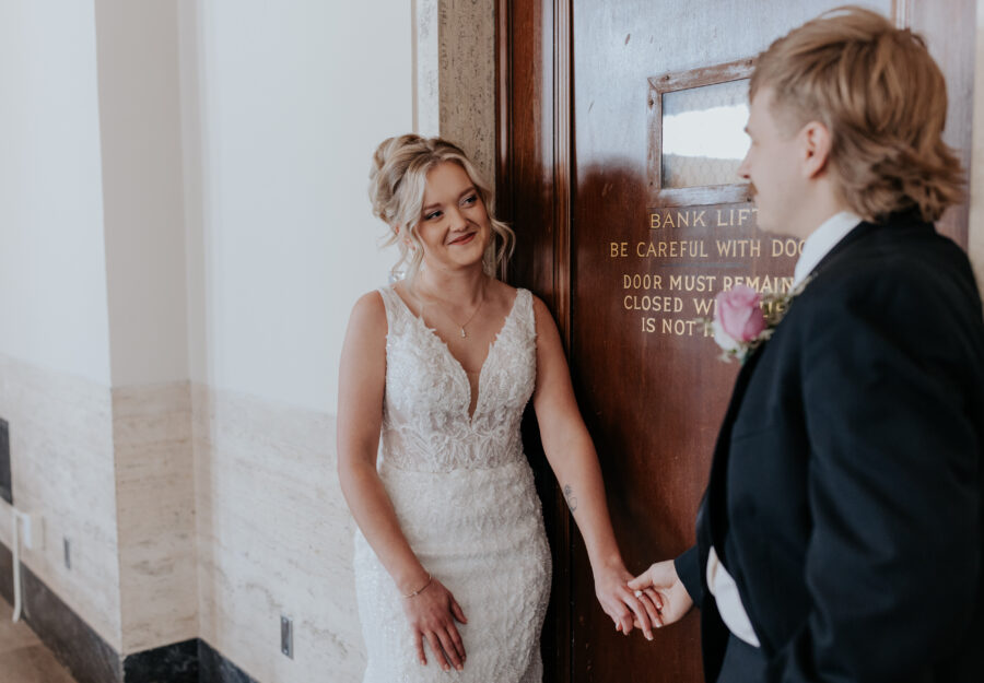 Bride and groom sharing a romantic moment beside a historic bank door inside The Reserve.
