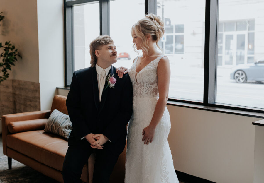 Bride and groom posing beside large arched windows inside The Reserve wedding venue.