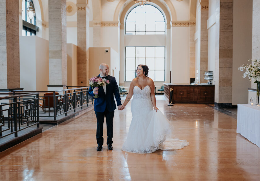 Newlywed couple walking hand in hand through the historic ballroom of The Reserve.